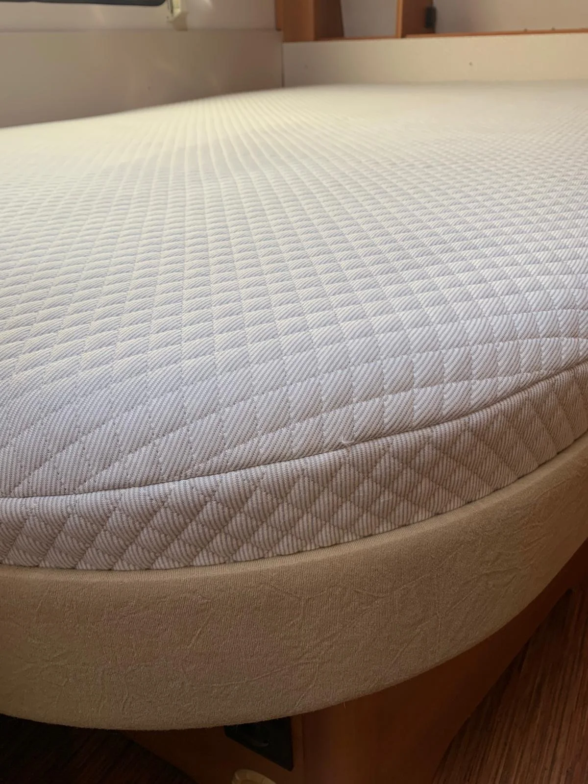 Close-up van een wit matras op maat met diamantgestikte tijk in een caravan