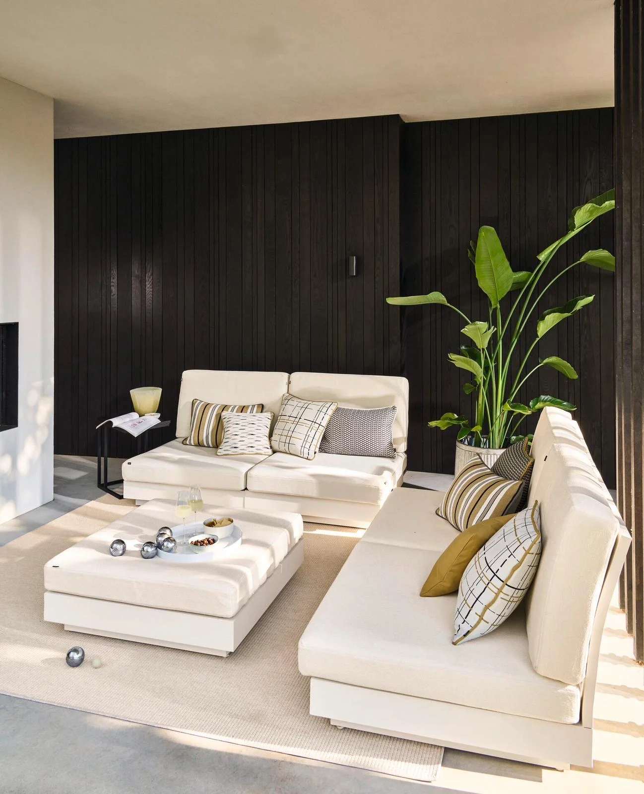 Modern interieur met crème gestoffeerde banken en zwarte houten wand — een opgeleverd project