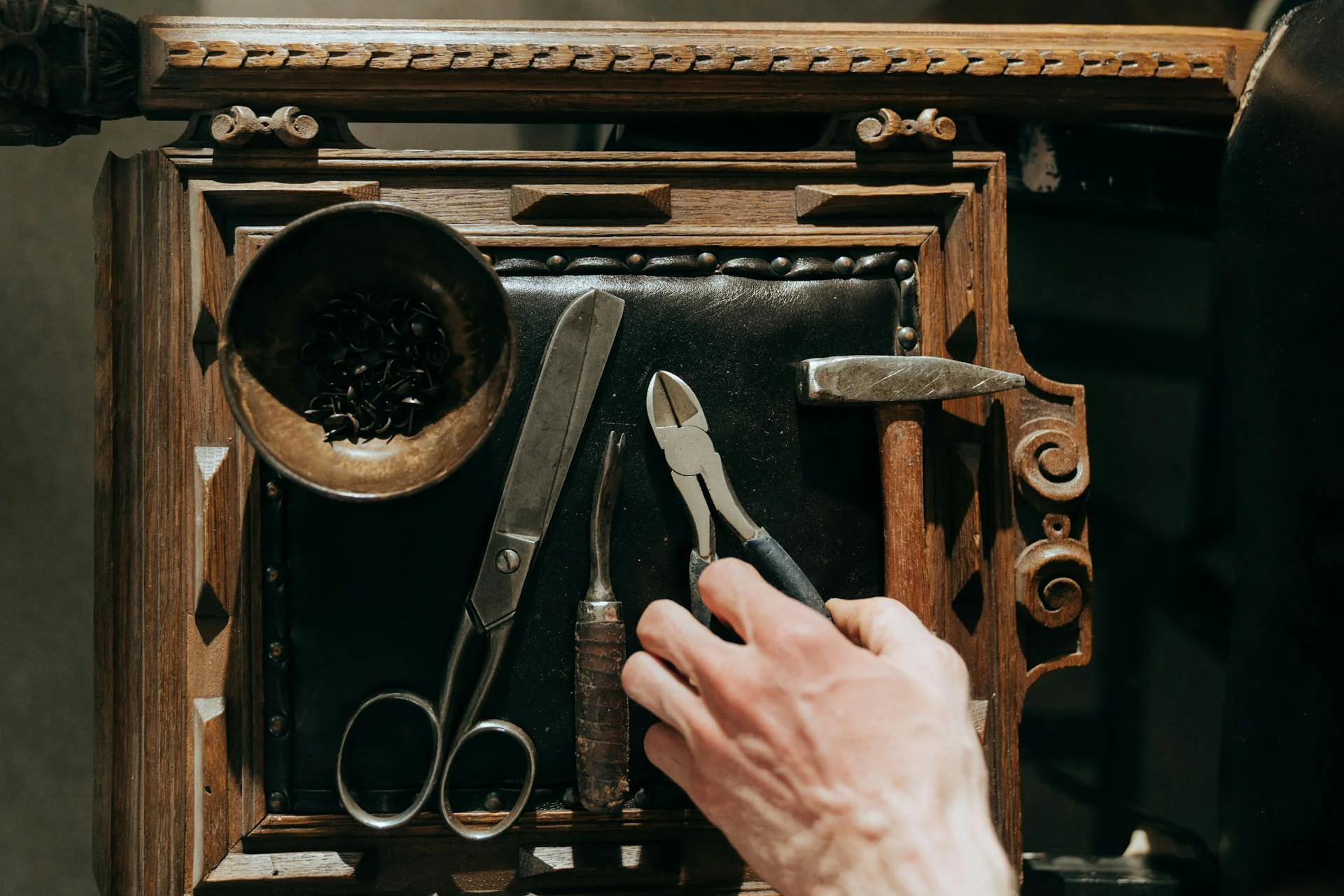 Gereedschap van een stoffeerder uitgelegd op een bewerkte houten rand in de werkplaats