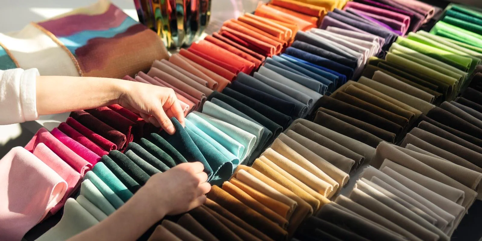 Kleurrijke collectie velvet stalen in alle kleuren — handen kiezen een staal uit de waaier